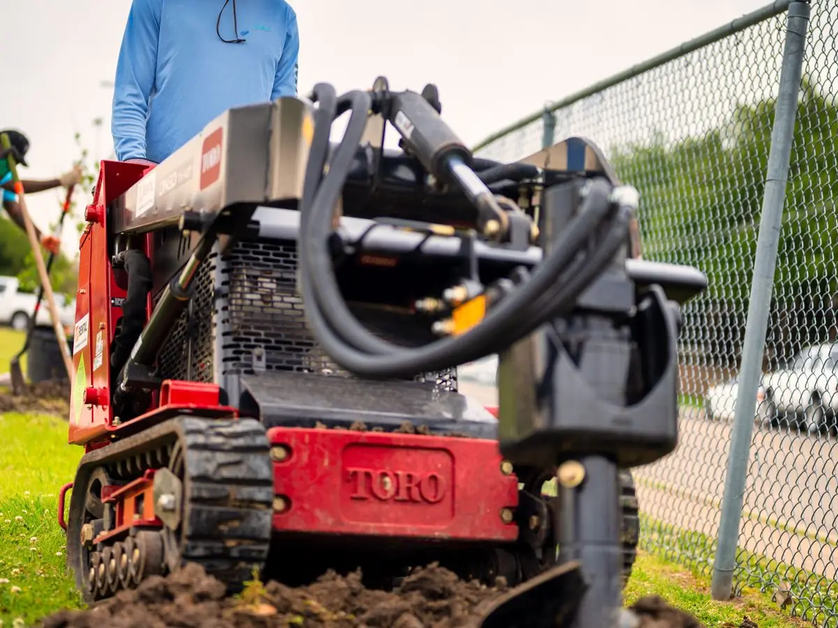 Walk-behind trencher cutting a French drain line across a lawn in Collin County TX
